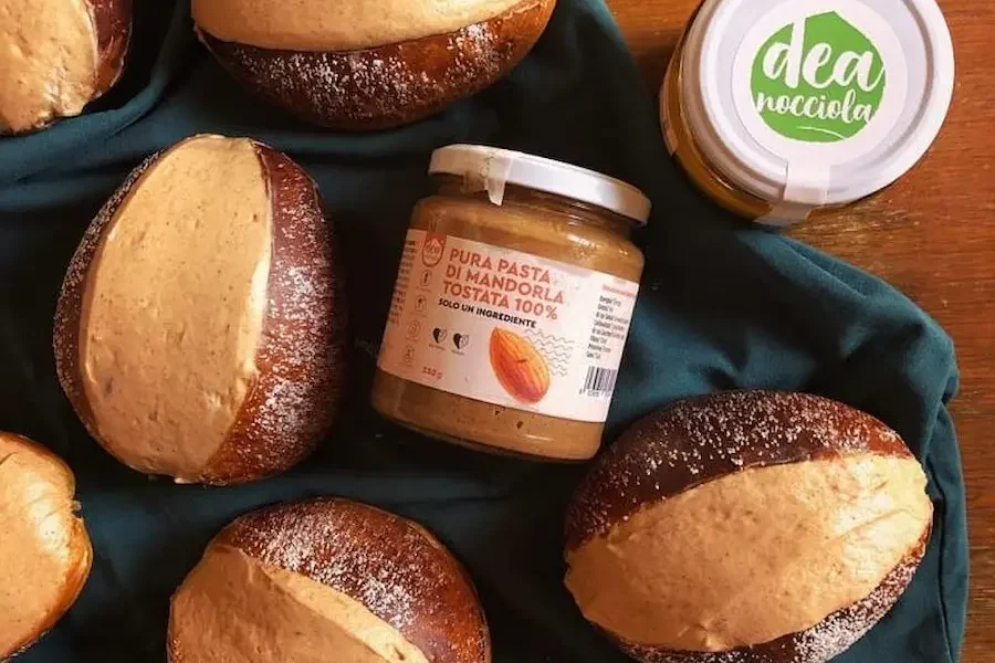 L immagine rappresenta Maritozzi farciti di panna e crema splamabile alle mandorle e 2 vasetti crema spalmabile di pura pasta di mandorle