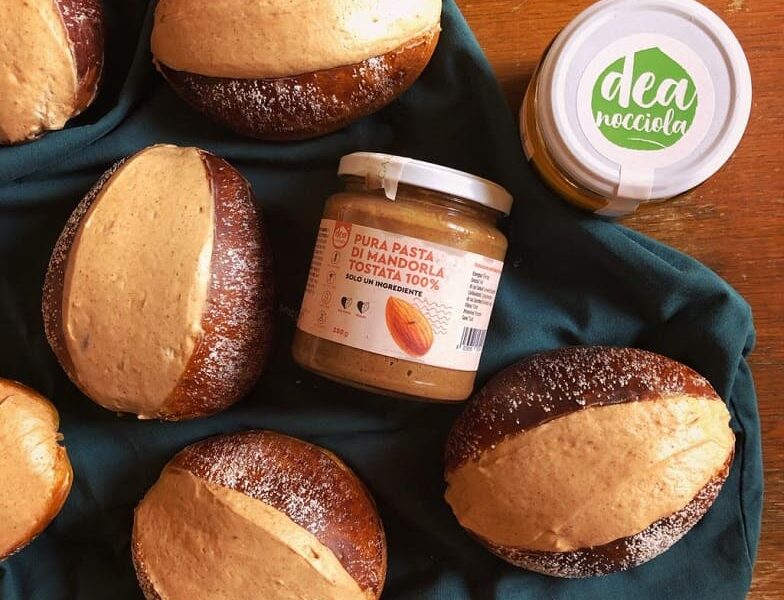 L immagine rappresenta Maritozzi farciti di panna e crema splamabile alle mandorle e 2 vasetti crema spalmabile di pura pasta di mandorle