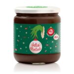 vasetto di crema fondente vegan con etichetta natalizia con sfondo verde scuro decorato da caramelle e stelline varie e al centro la mano del grinch che tiene una pallina di natale con scritto odio il natale