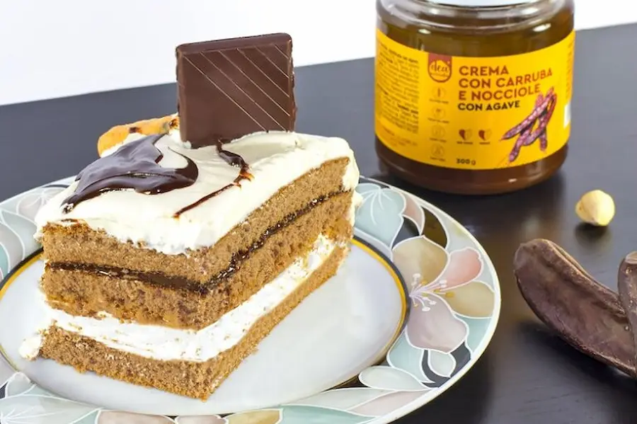 Torta carrube e banana su un piatto , vasetto crema carruba e nocciola e barrette di cioccolato