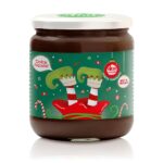 vasetto di crema fondente vegan con etichetta natalizia con sfondo verde scuro decorato da caramelle e bastoncini di natale con al centro le gambe di un elfo a testa in giu con calze a righe e vestito rosso