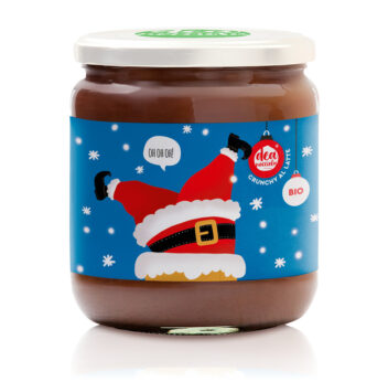 vasetto di crema al latte crunchy con etichetta natalizia con sfondo turchese e fiocchi di neve e al centro babbo natale incastrato in un camino che dice oh oh oh