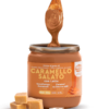 vasetto di crema con cucchiaio di legno immerso nella crema con a fianco 4 cubetti di caramello